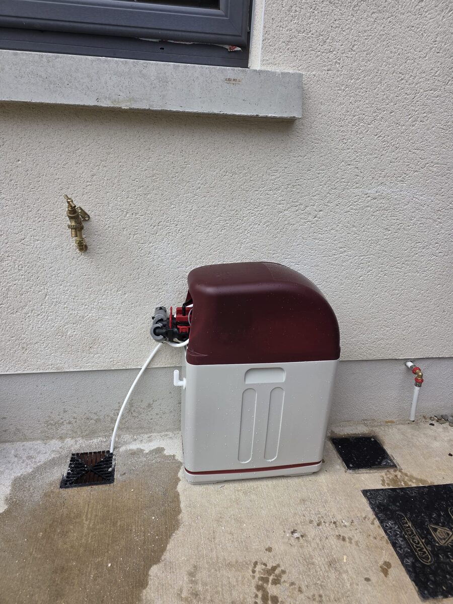 Compact softener installed outside a new build with brass garden tap nearby