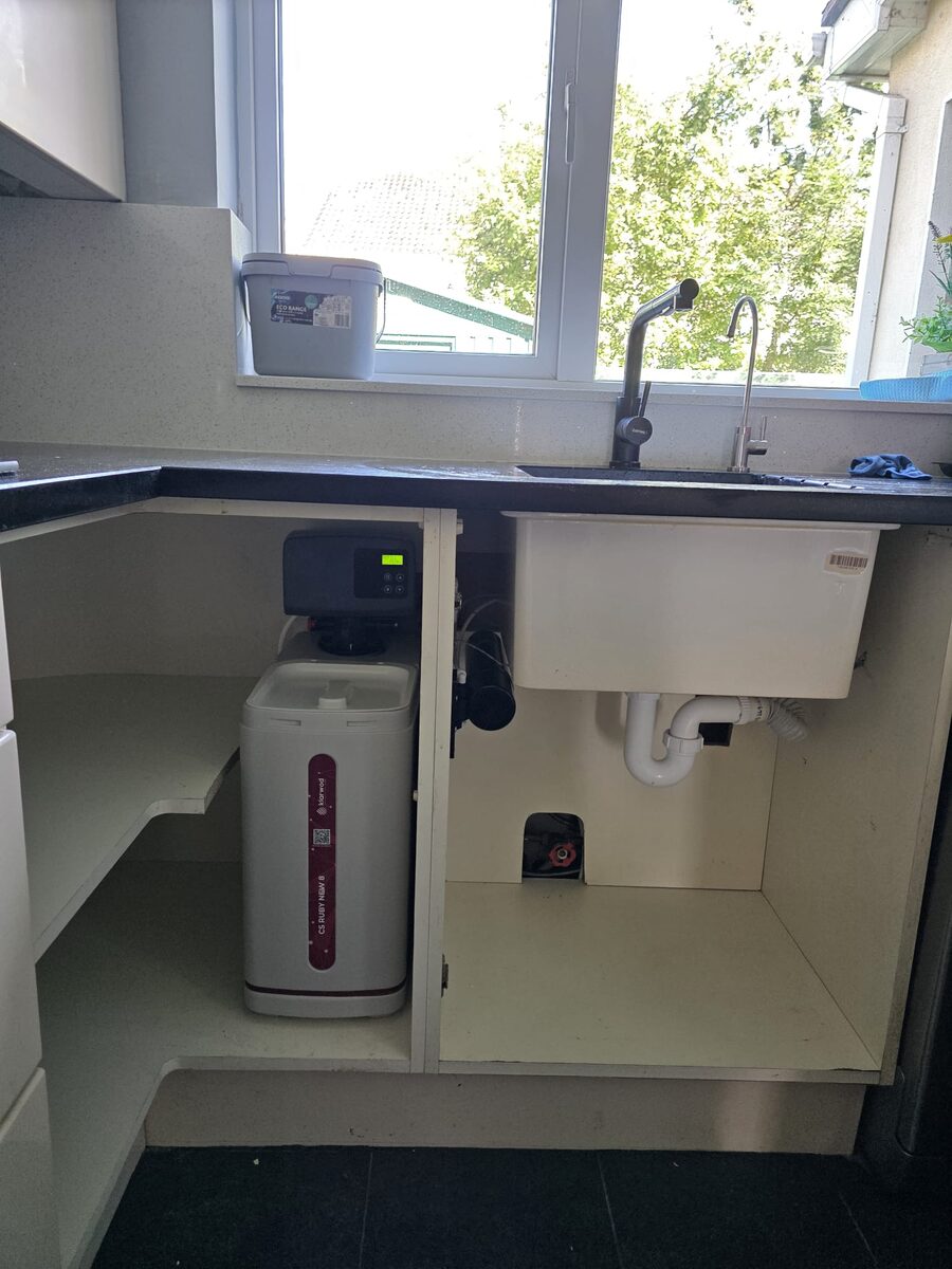 Softener fitted in a utility room cabinet beside a Belfast-style sink